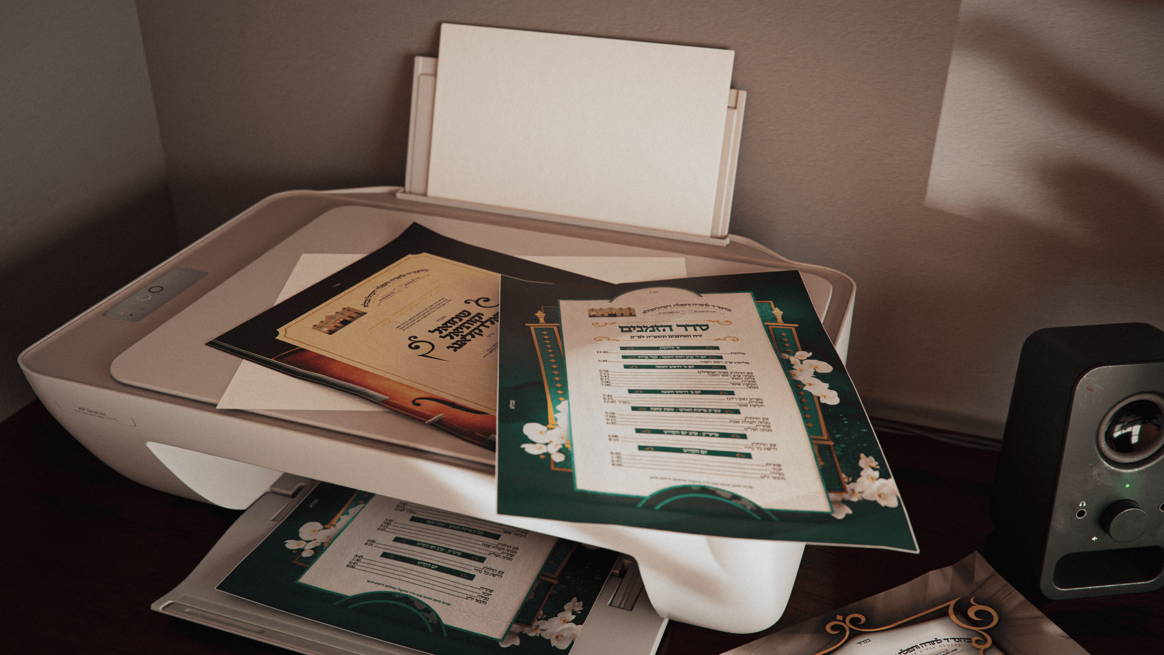 7 Printed shul posters created with the Tavlah program placed on a printer, showcasing vibrant designs and detailed layouts.